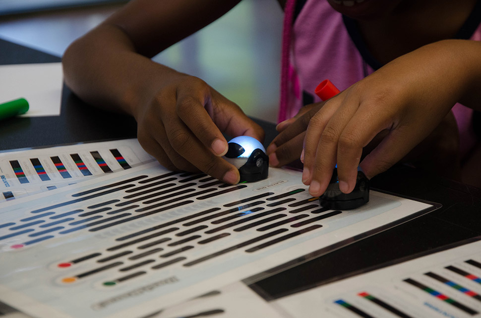 Children play with robots that follow color patterns during a Perot Museum Tech truck stop at the Park in the Woods Rec Center in Dallas.  [ Photo by Hannah Ridings ]