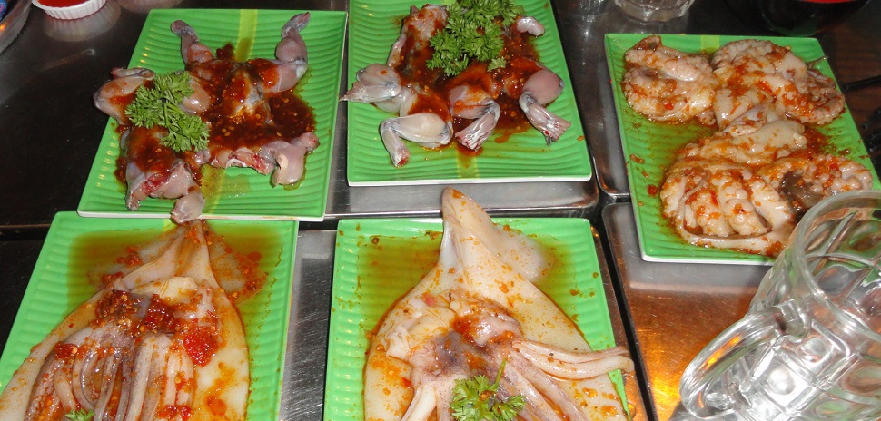 Squid, with octopus on top of it and frog before being popped onto a table grill.
