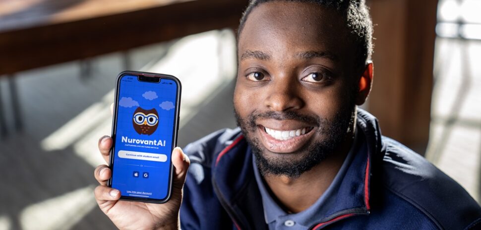 SMU student-entrepreneur Trevor Gicheru, smiling, and posing next to the study app he created.