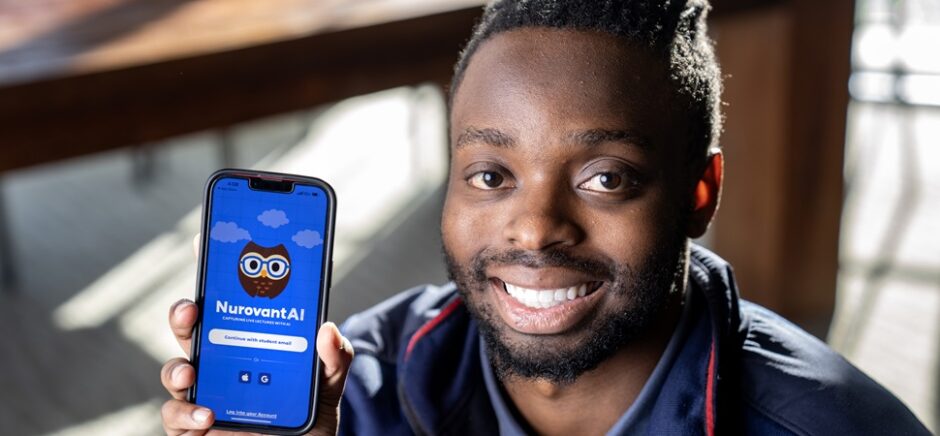 SMU student-entrepreneur Trevor Gicheru, smiling, and posing next to the study app he created.