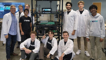 John Lauer (left) and members of the Adom Industries team gather around the company’s “workcell”—the core of its cloud-connected electronics prototyping factory. Lauer likens the system to “compute for atoms,” much like a server in a data center enables “compute for bits,” calling it the Amazon Web Services of electronics prototyping. The photo was taken shortly after a major presentation to a leading electronics company, following months of preparation.