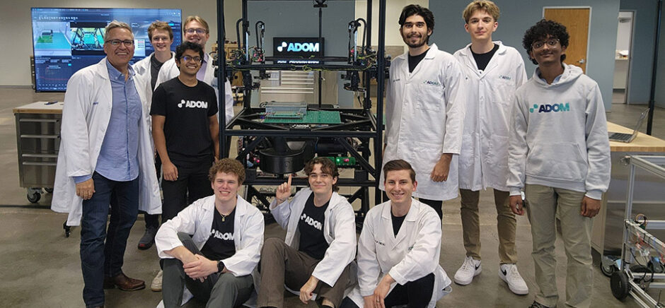 John Lauer (left) and members of the Adom Industries team gather around the company’s “workcell”—the core of its cloud-connected electronics prototyping factory. Lauer likens the system to “compute for atoms,” much like a server in a data center enables “compute for bits,” calling it the Amazon Web Services of electronics prototyping. The photo was taken shortly after a major presentation to a leading electronics company, following months of preparation.