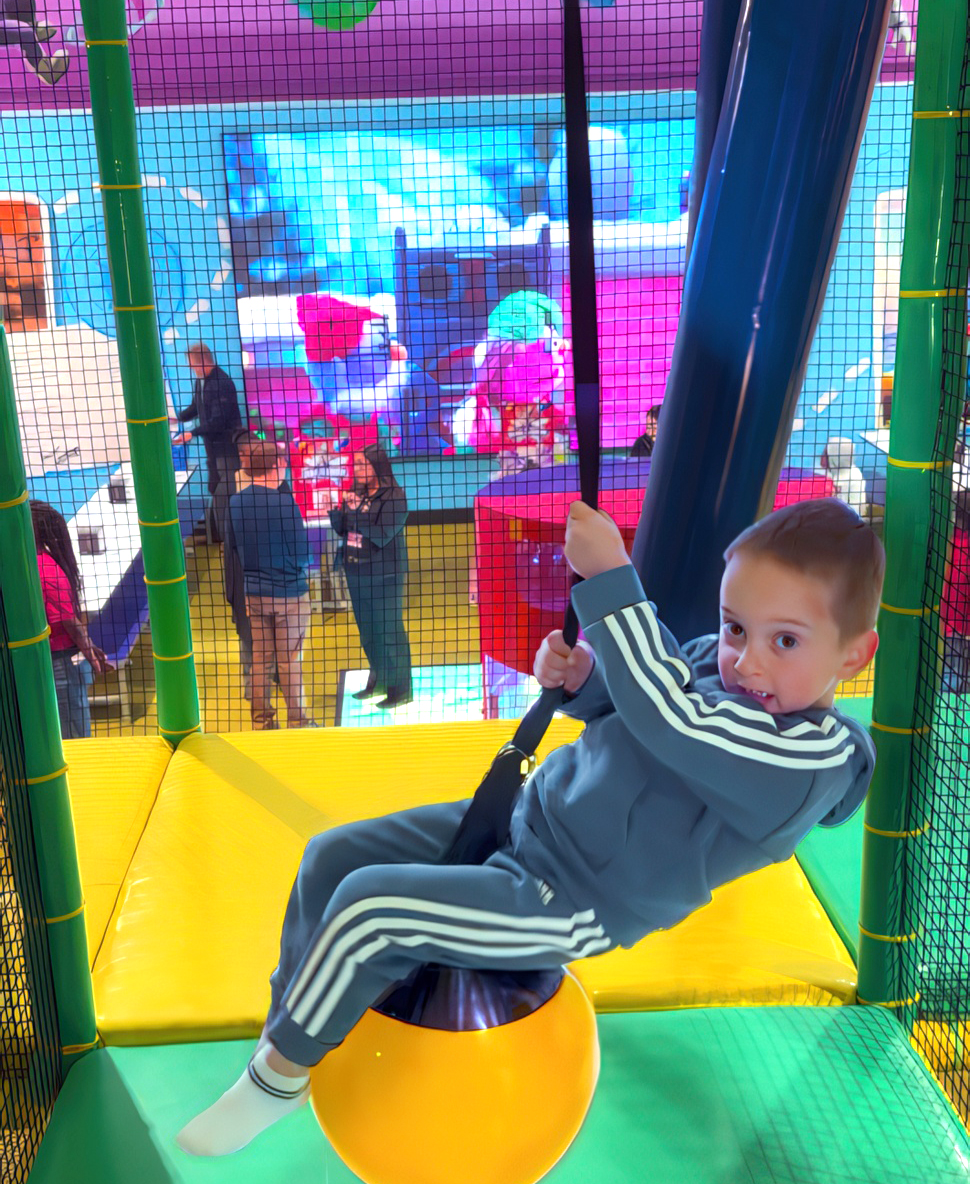 A young guest hangs onto a swinging padded ball in the multi-level play area. [Photo: Dallas Innovates]